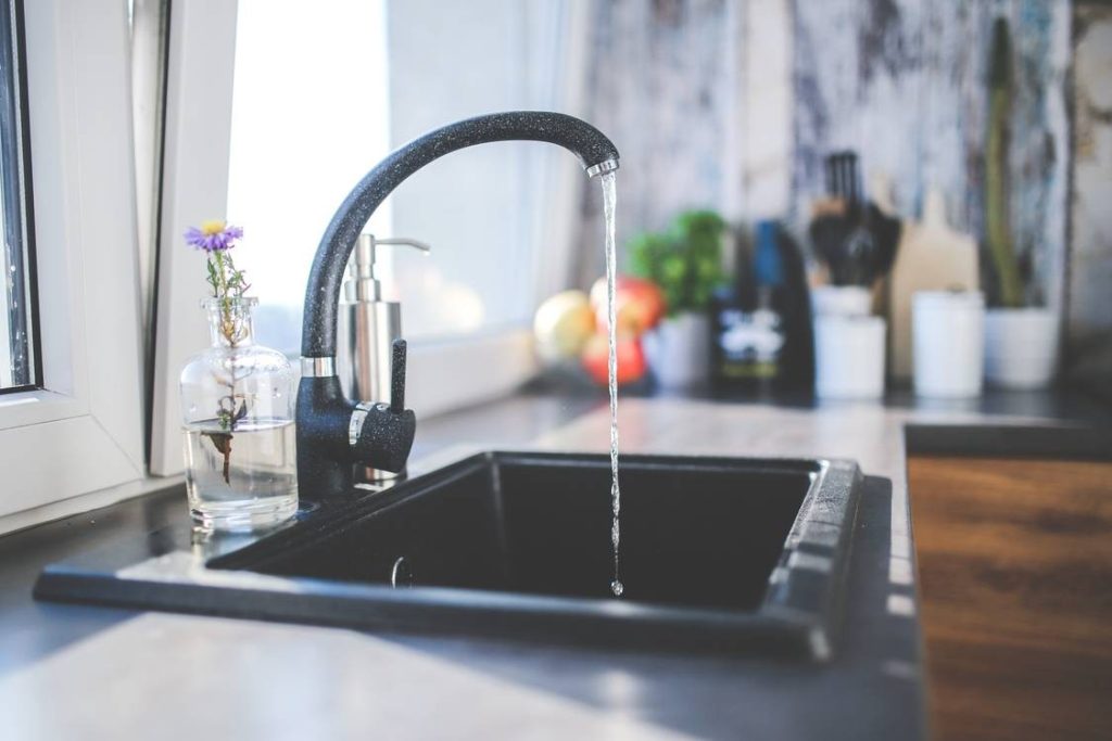 A tap in a kitchen sink is turned on and producing hot water.