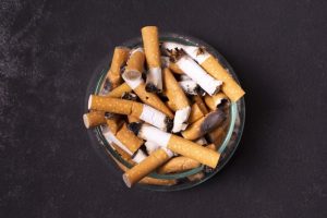 cigarette butts in an ashtray on a dark grey ground