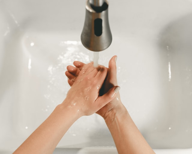 A person washing their hands in a white sink