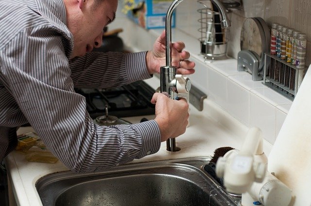A man attempts to fix a clogged kitchen sink