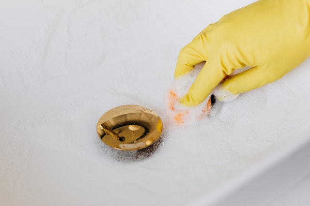 Cleaning the bathroom sink while wearing yellow gloves