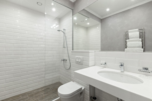 A bathroom with white tiles and silver plumbing fixtures