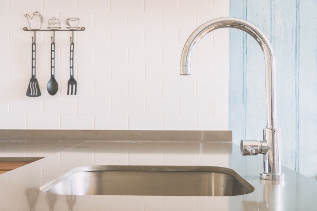 a side view photograph of a clean and well-maintained silver kitchen sink