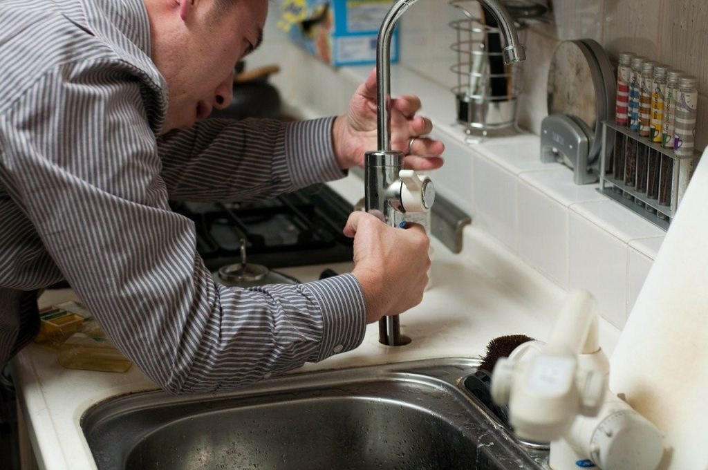 A plumber works on a leaky faucet, which causes water to go to waste and can be a cause for concern.