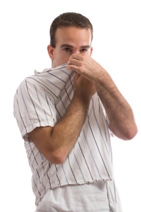 A man in a white shirt covering his nose due to the bad smell.