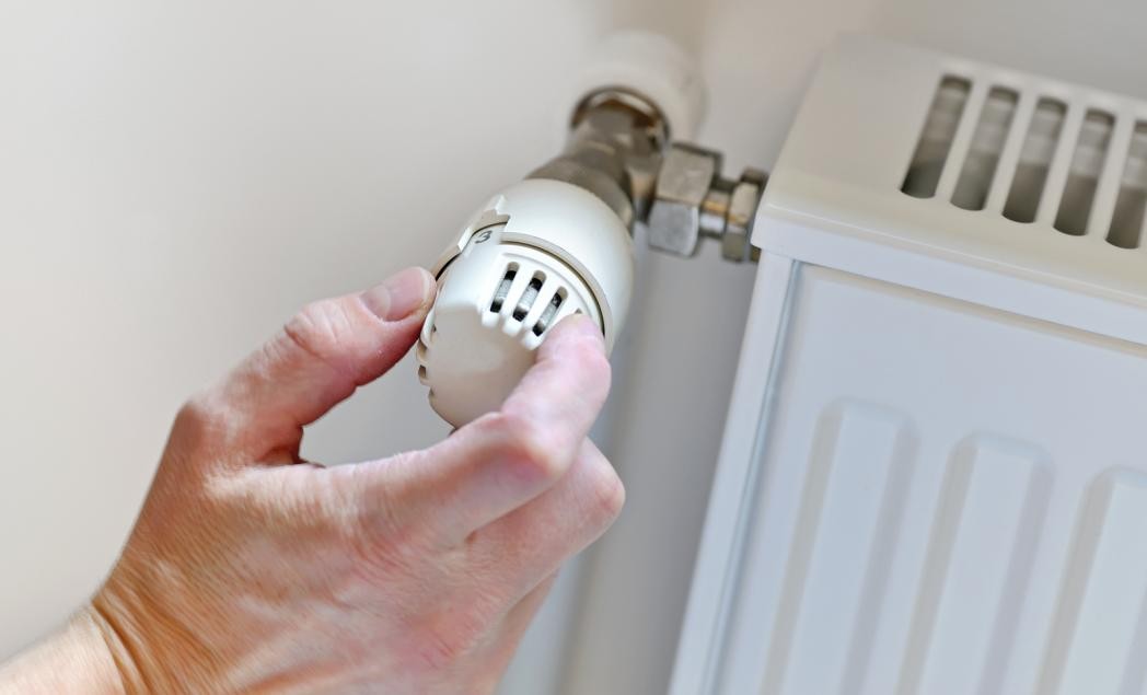 A plumber adjusting the thermostat of a water heater.