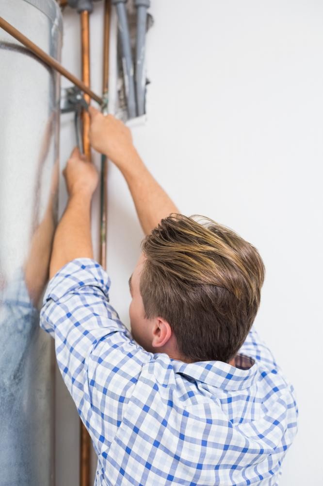 A young plumber repairing a water heater