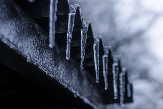 Frozen icicles hanging on a roof’s edge