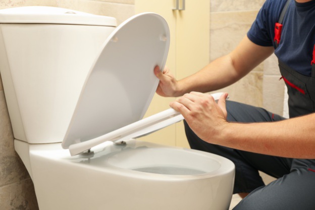 Plumber fixing malfunctioning toilet