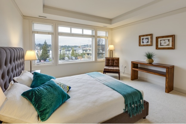 A bedroom with green pillows and white walls