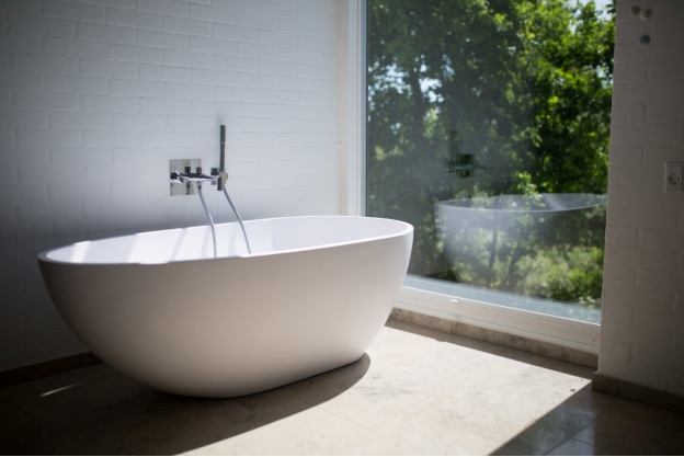 A white ceramic bathtub near a window