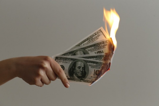 Dollar bills being burned as a sign of losing money