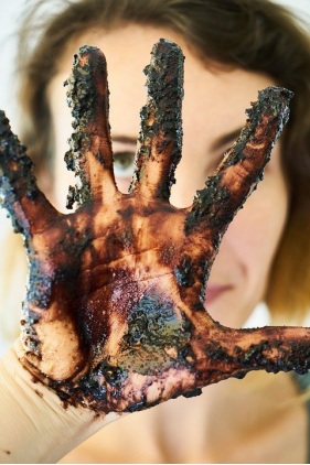 Woman’s hand covered in different colored debris