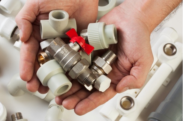 A man holding plumbing parts and fixtures for DIY repairs