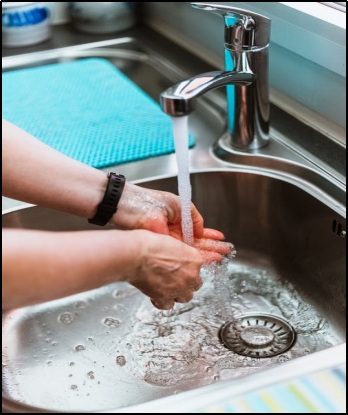 woman washing hands under running tap water